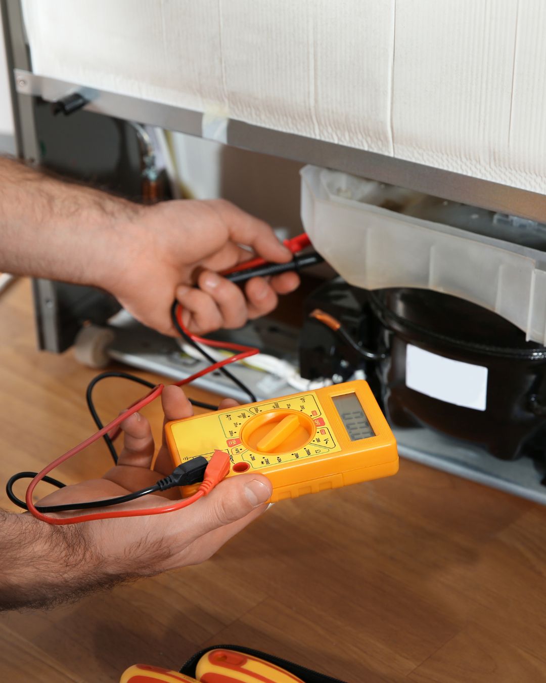 Technicien utilisant un multimètre pour diagnostiquer une panne de réfrigérateur à Charlemagne