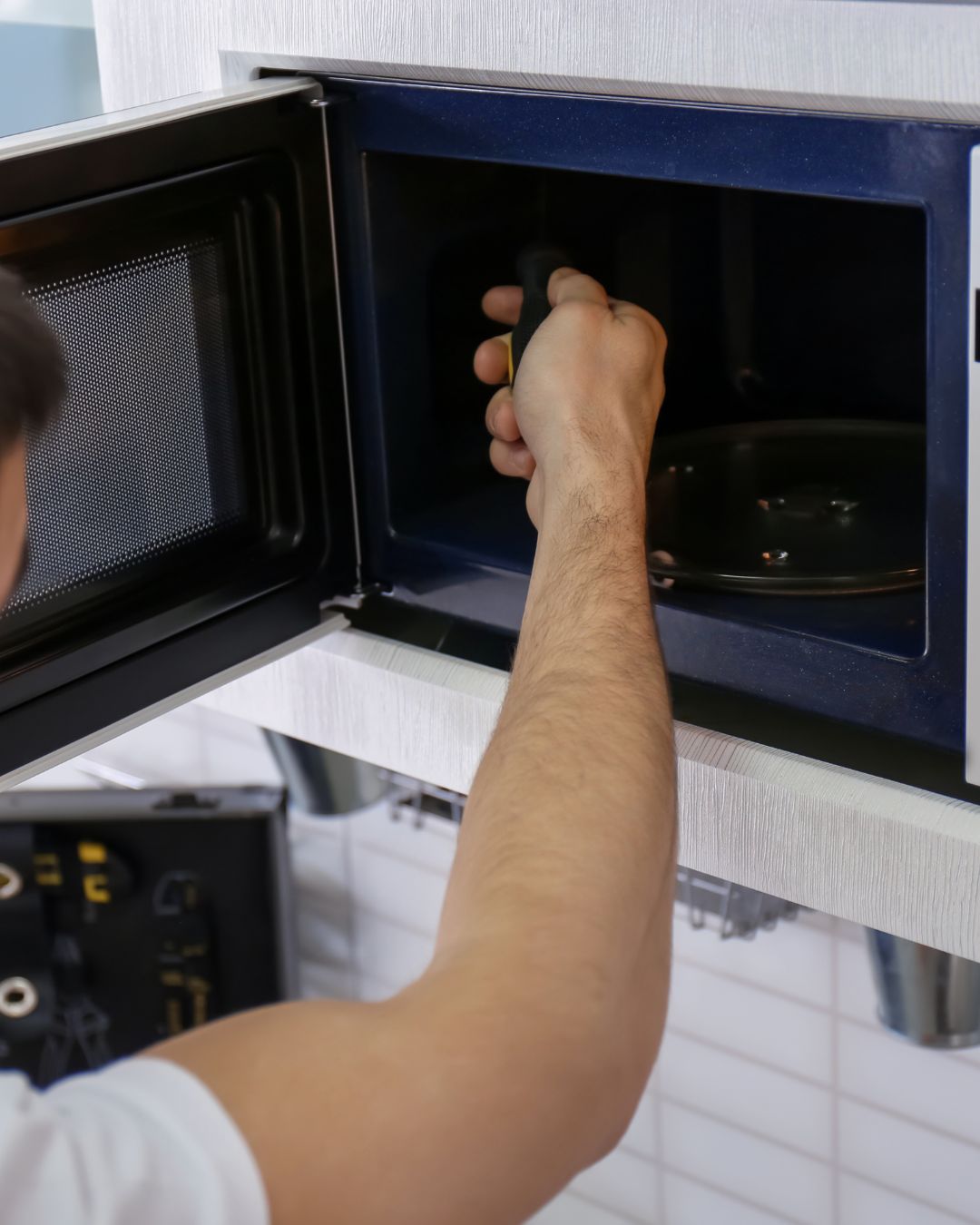 Technicien réparant un four micro-ondes résidentiel à Terrebonne-Ouest